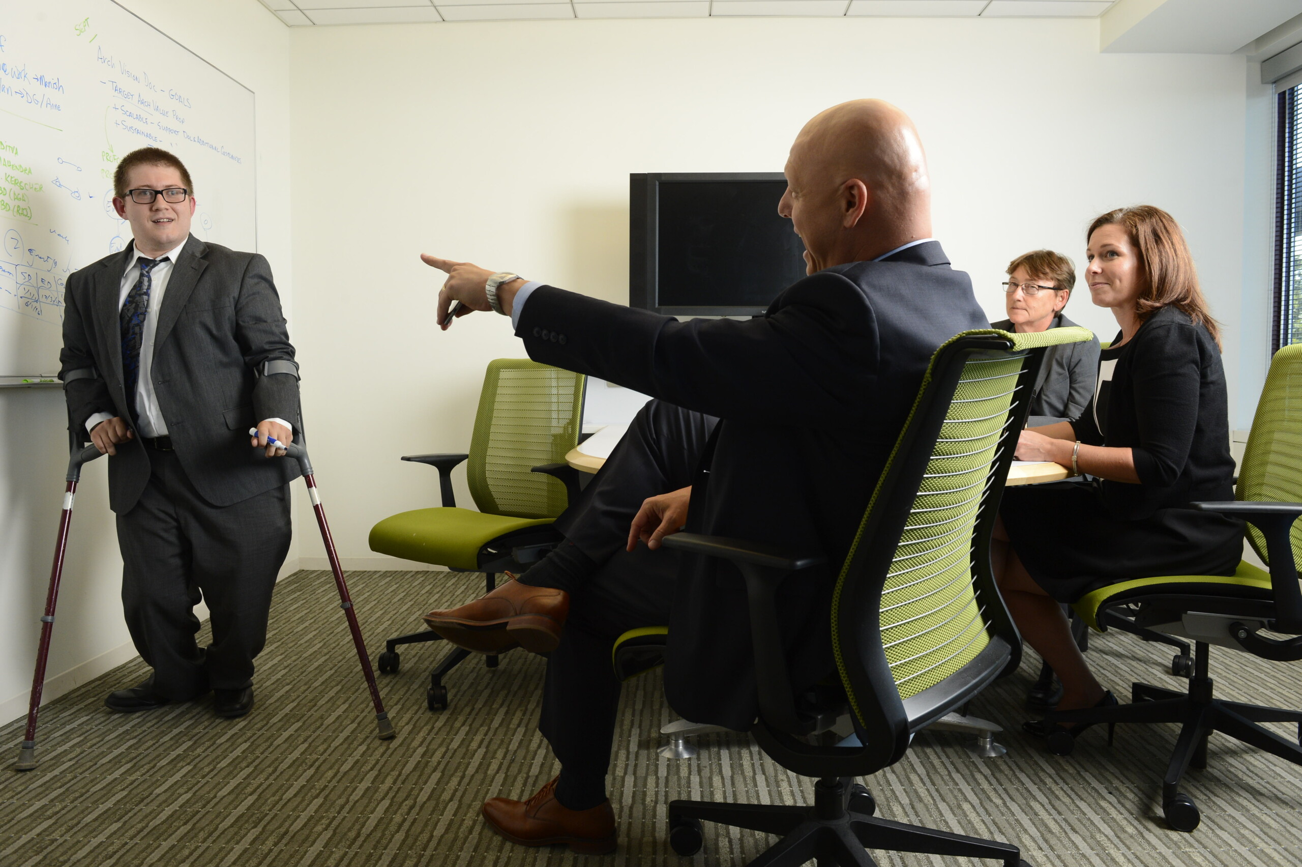 Employee giving a presentation while using forearm crutches Employee giving a presentation while using forearm crutches
